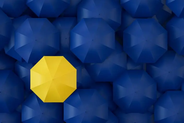 A single yellow umbrella standing out among blue umbrellas