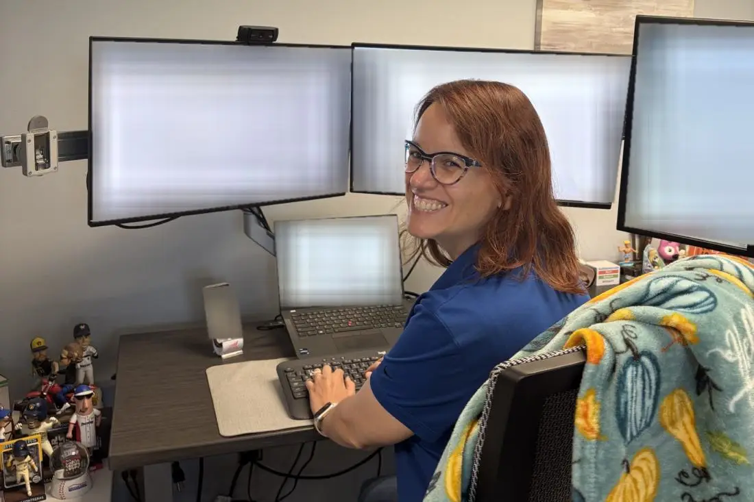 A CCB Technology service desk team member smiling at her workstation.